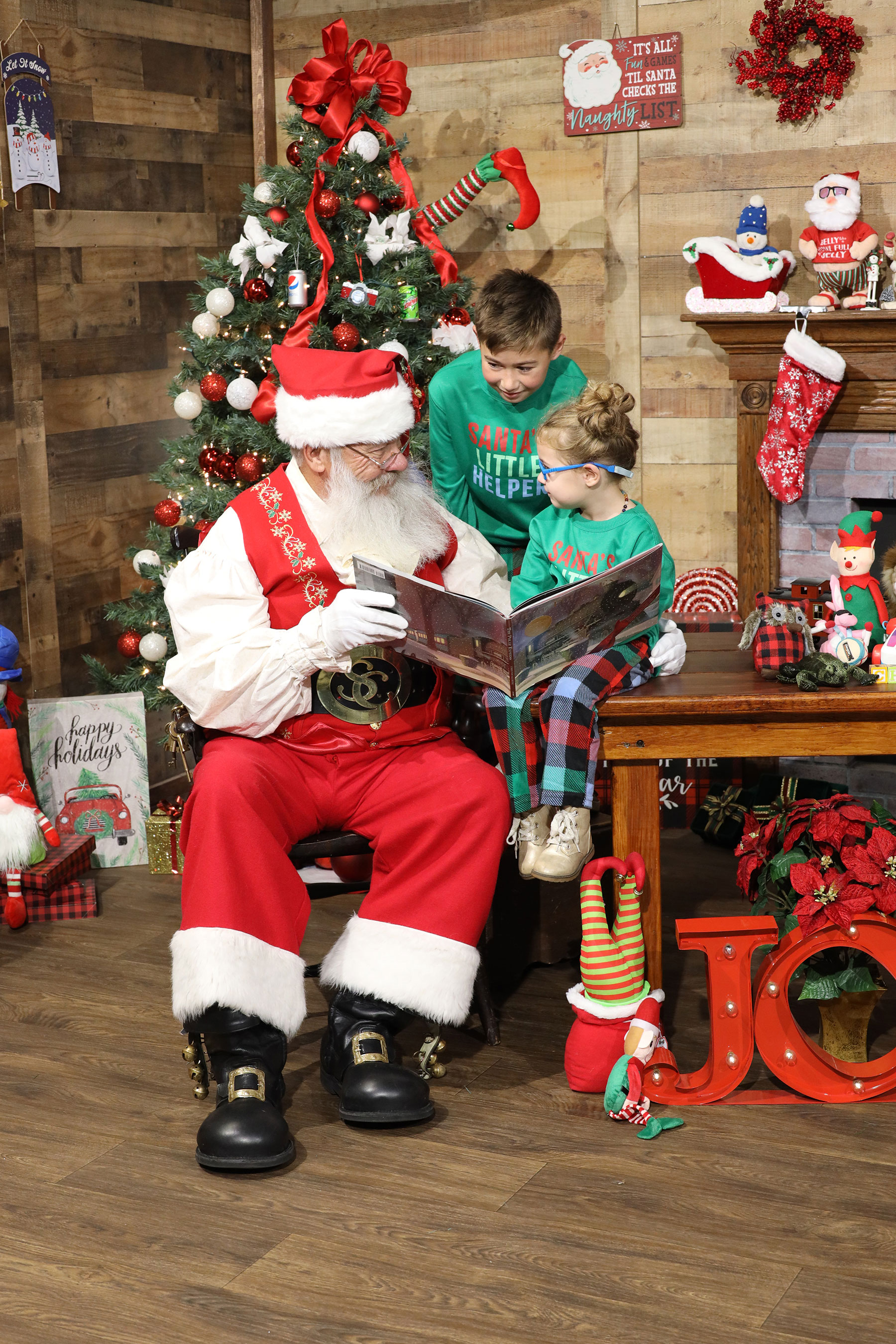 Santa reading to two small children in Santa's workshop inside Kurt Nielsen Photography, Inc. Portrait Studio