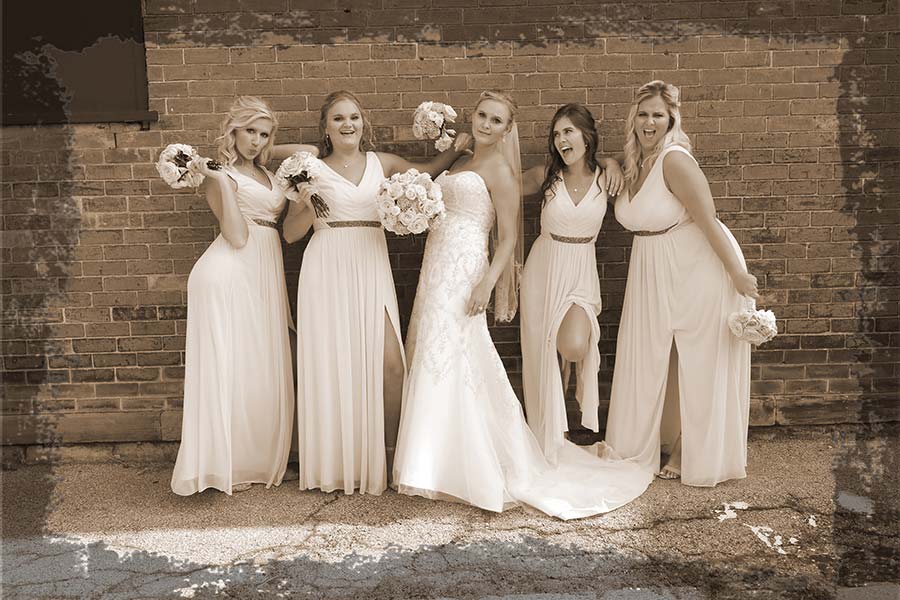 the bride and her bridesmaids having fun in their long pink gowns in downtown Perrysburg