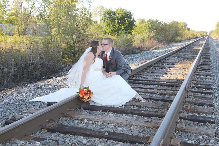 the bride and groom enjoying a kiss while posing on the train tracks in Rossford, Ohio