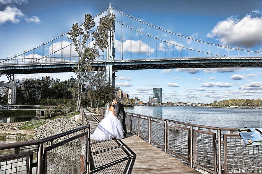 bride and groom stopping for a kiss under the blue bridge over the Maumee River in toledo