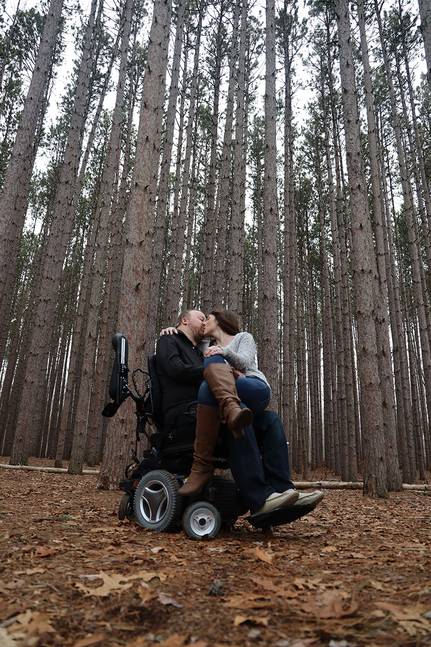 disabled groom to be in his motorized wheelchair with his bride to be on his lap at The Spot in Oak Openings MetroPark