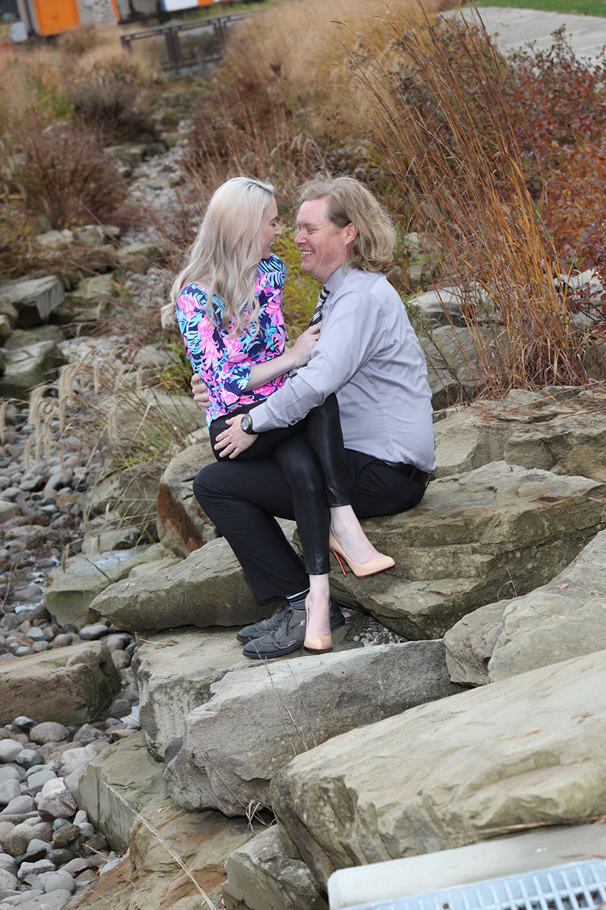 girl sitting on guys lap on rocks near the stream at Middlegrounds MetroPark behind Owens Corning in downtown Toledo