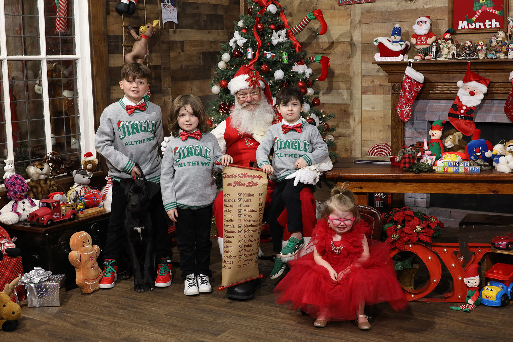 three brothers in matching shirts and crying sister posing with Santa at Kurt Nielsen Photography