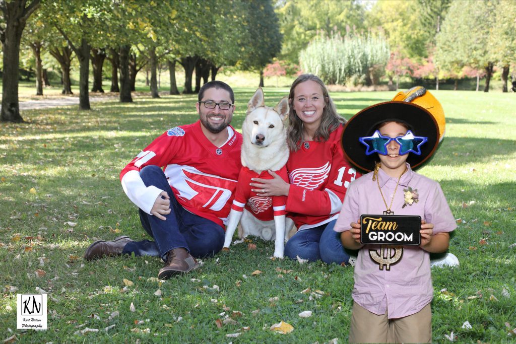 nephew of the groom holding a team groom sign in front of the bride and groom and their dog