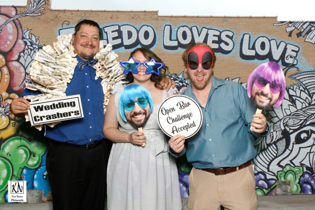 friends of the bride and groom using props in front of the Toledo Loves Love mural