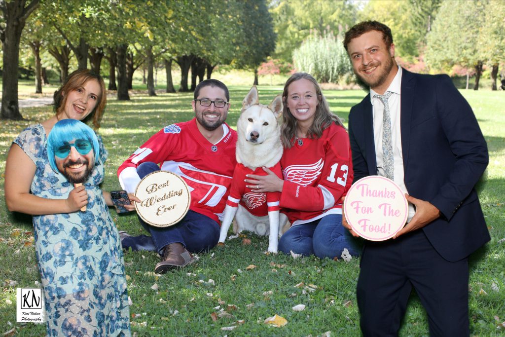 friends of the bride and groom posing with them for a photo in the photo booth