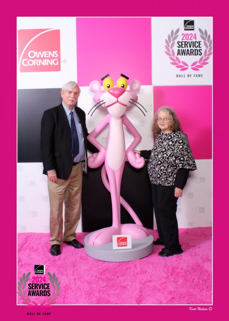 older couple posing with the Pink Panther life-sized bobble head at the 2024 Owens Corning Service Awards at their headquarters in downtown Toledo.