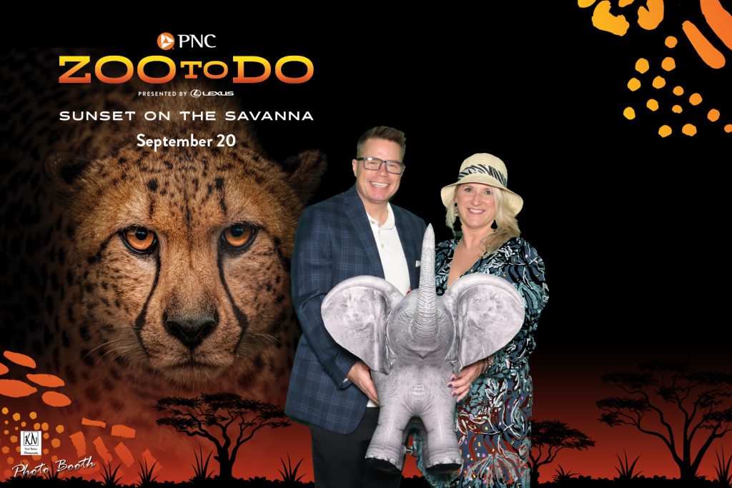 couple holding an inflatable elephant in a green screen photo at the Toledo Zoo to Do