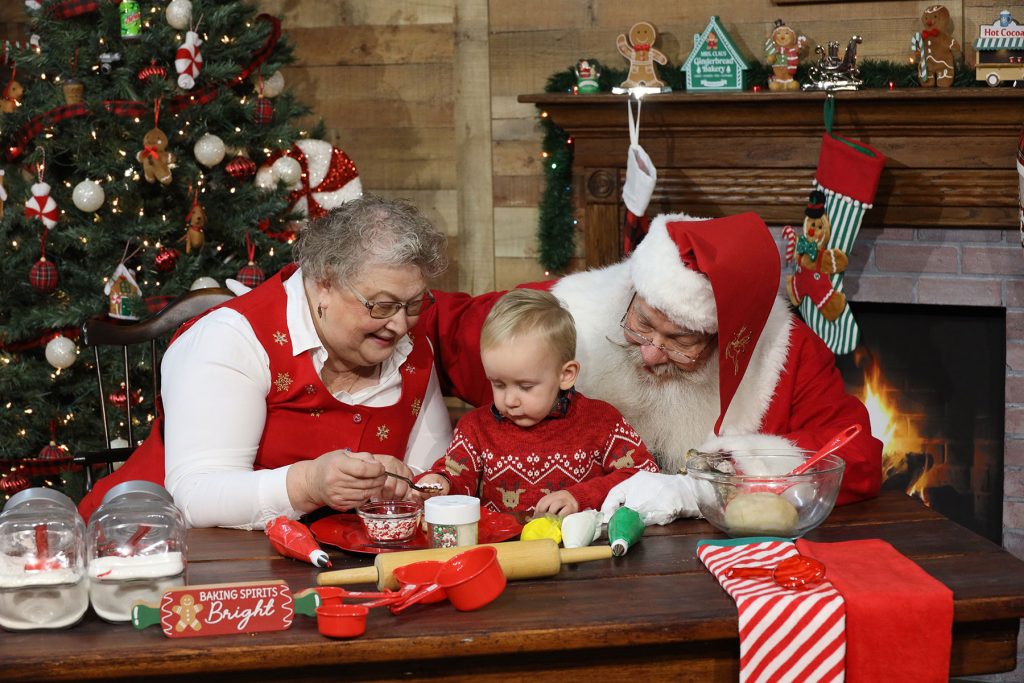 two year old boy decorating cookies with Santa and Mrs. Claus at Kurt Nielsen Photography