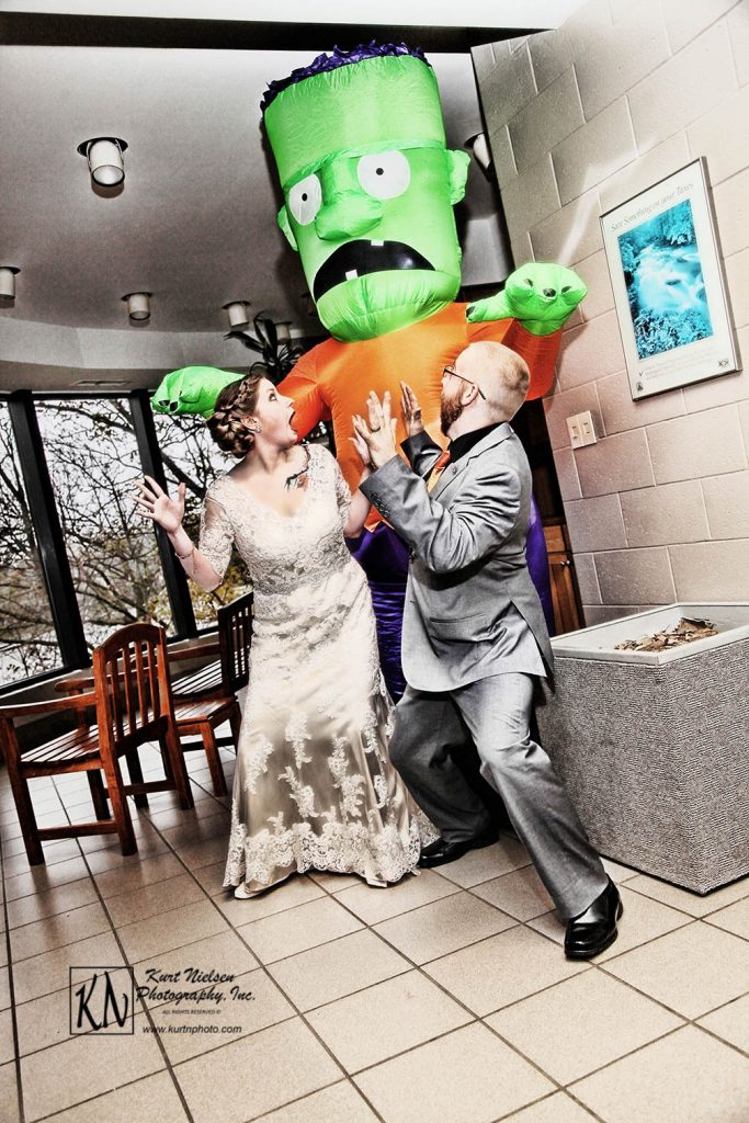 fun halloween photo of bride and groom being chased by blow up frankenstein
