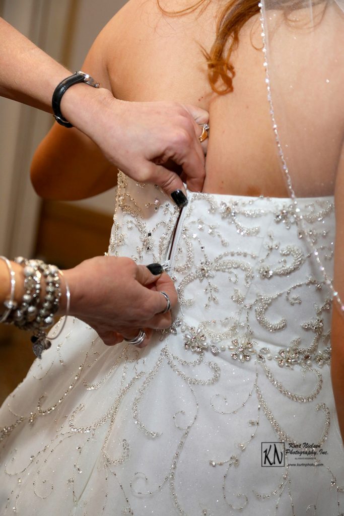 zipping the bride's dress