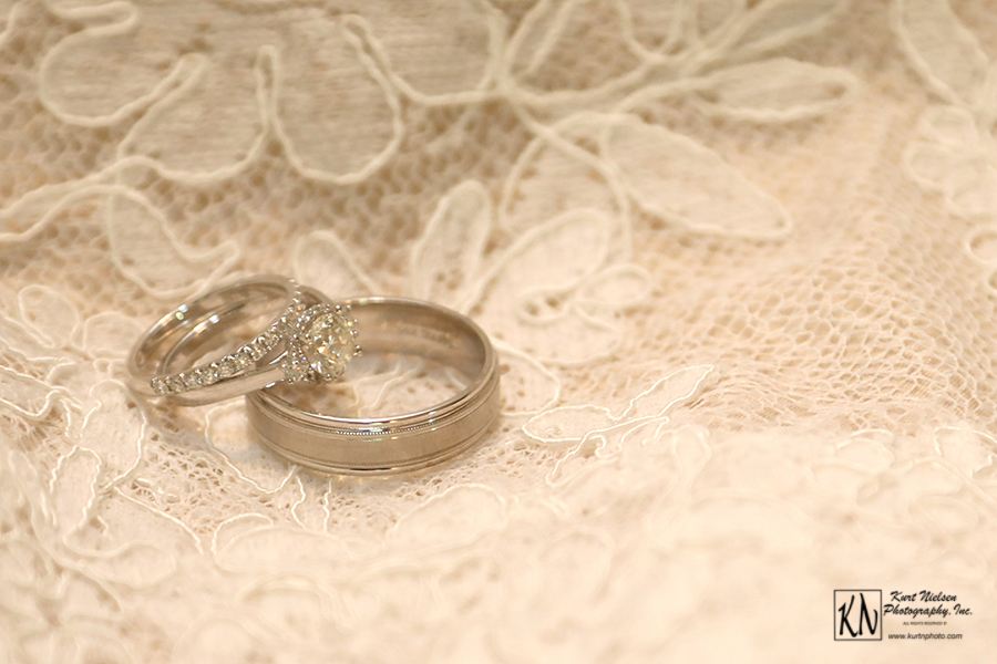 wedding and engagement rings on the brides lace gown