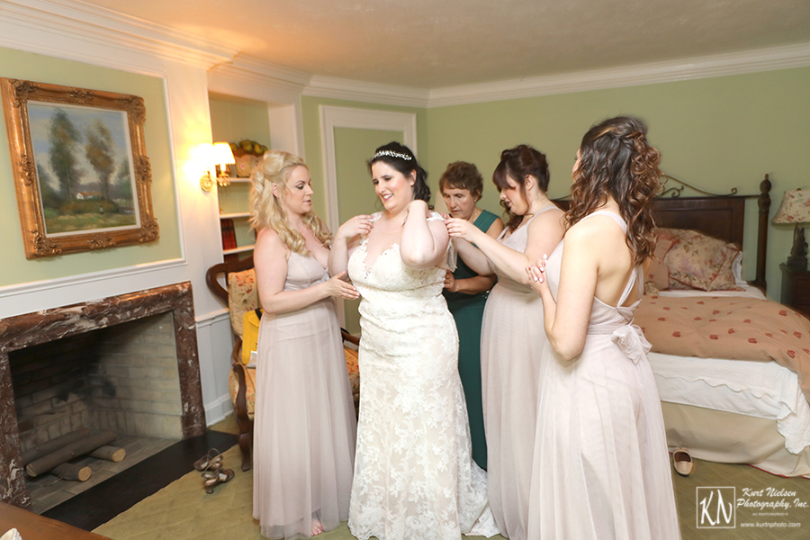 the bridesmaids helping the bride get dressed at the Club at Hillbrook