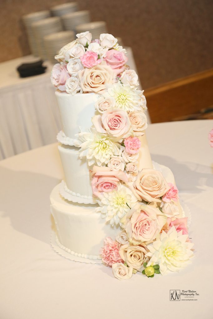fresh cut blush nude and white flowers cascading down a fondant covered wedding cake at The Pinnacle