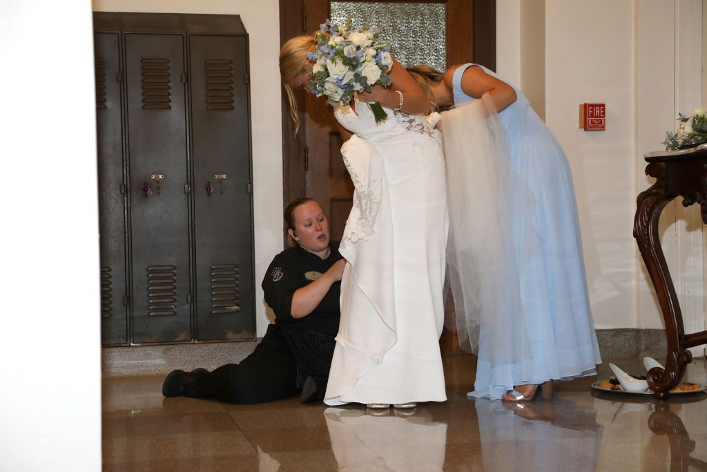 A Staff member at Nazareth Hall helping bustle the bride's dress.